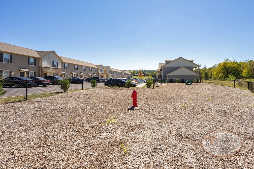 A dog park with seating, water station for pets, pet waste pick-up station, and obstacles for your dog to play on.