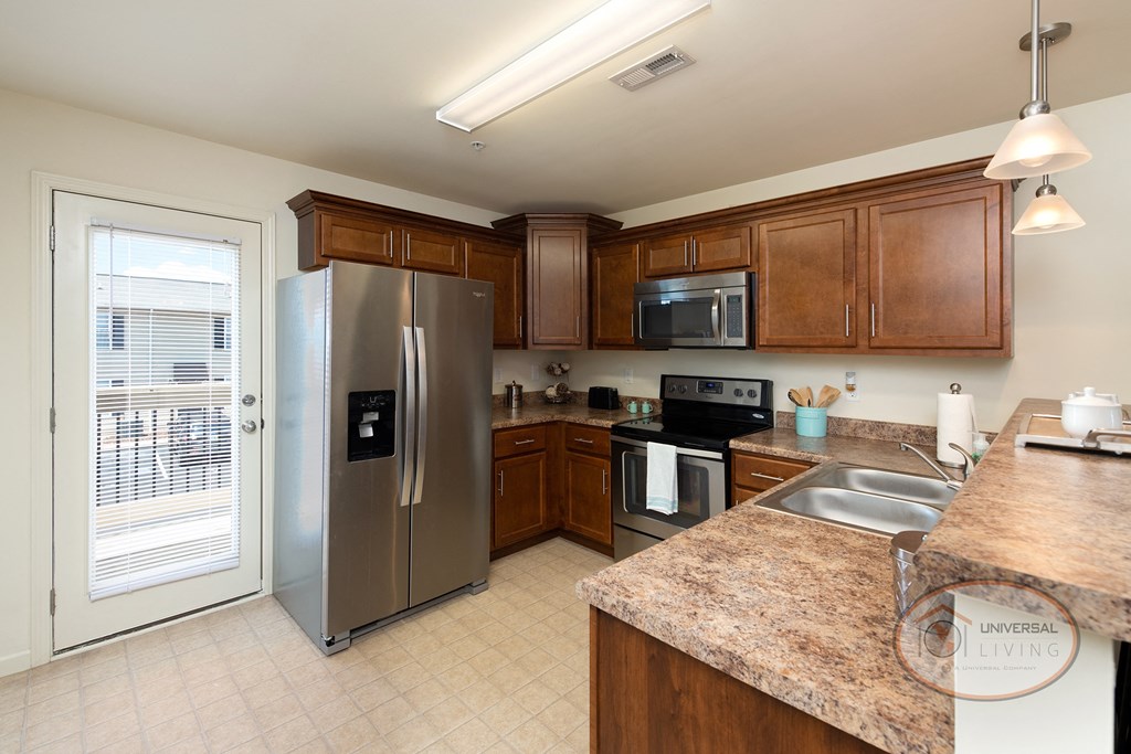 A kitchen with granite countertops, dark cabinets, and stainless steel appliances.