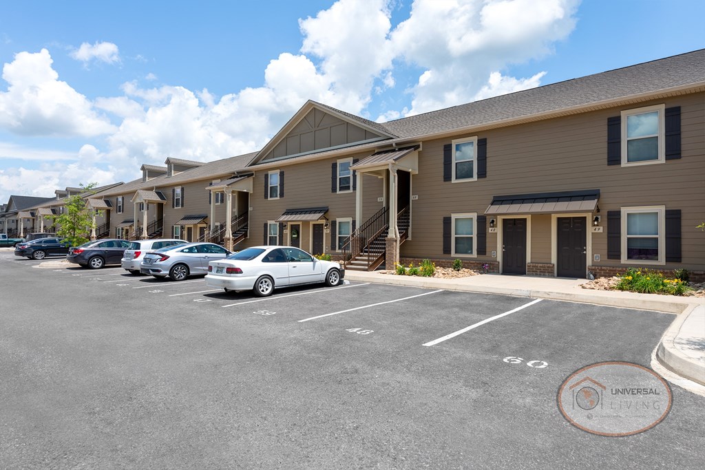 1 bedroom stacked apartment homes with tan siding and dark doors.