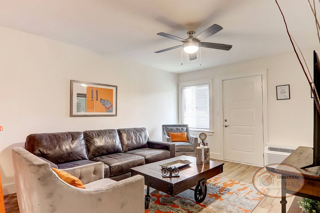 a living room with leather furniture and a ceiling fan