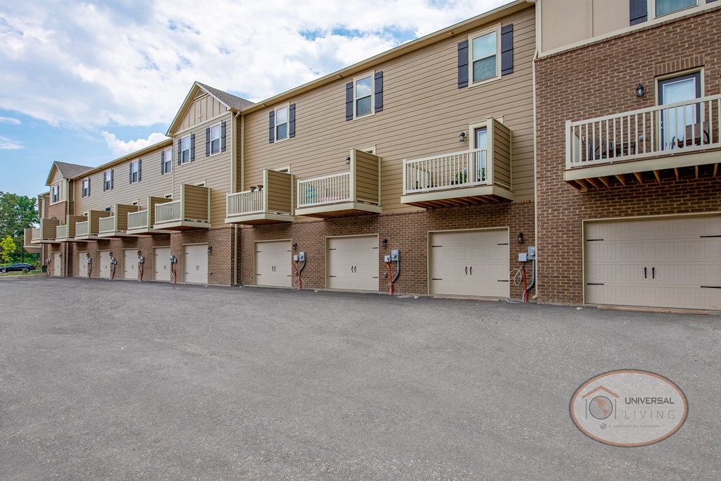 a row of units with white garage doors in front of a brick building
