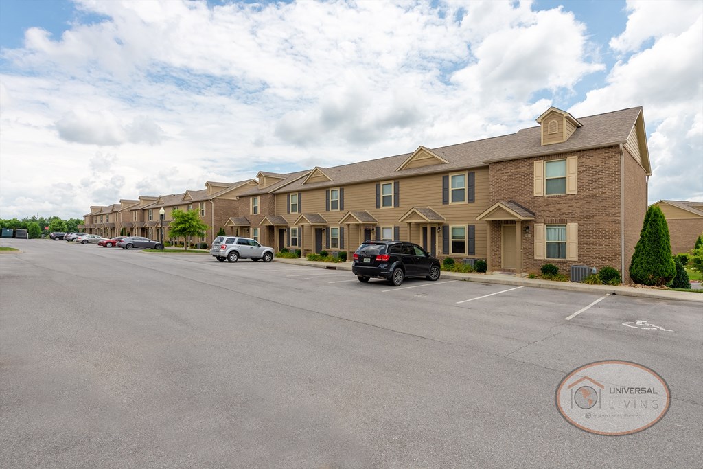 The front of a tan and brick two bedroom apartment home.