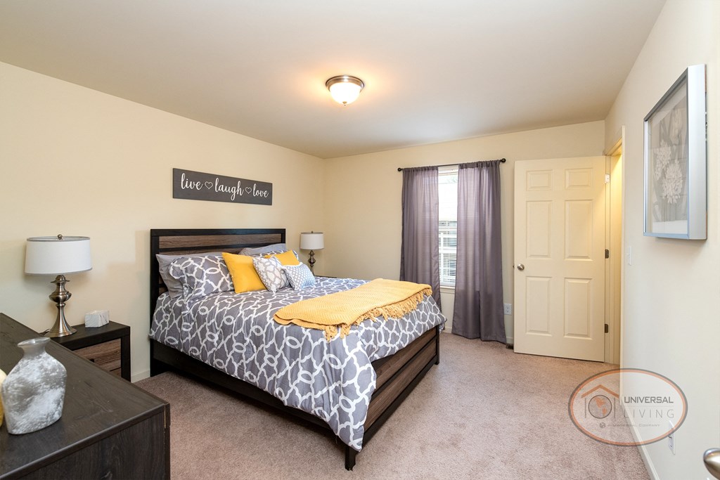 Pickens Bridge Village Apartment Homes For Rent, Piney Flats, Tennessee. A bedroom with a large bed, dresser, carpet, and white walls.