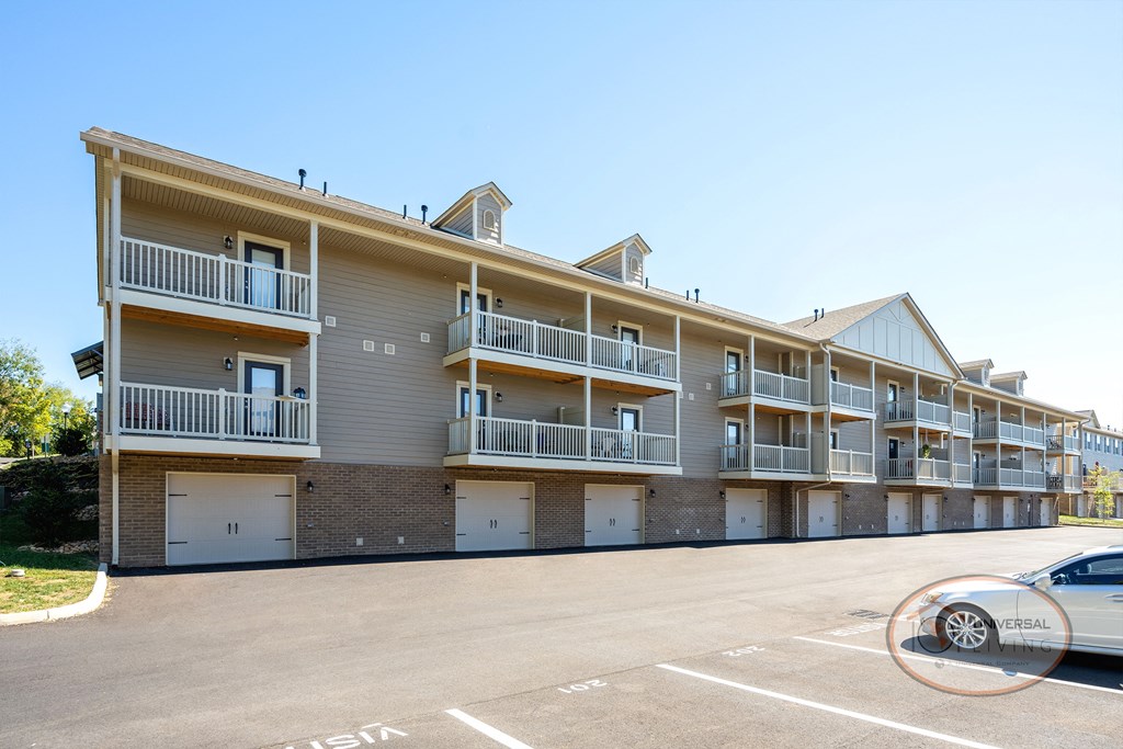 A tan, two story apartment building with ample parking, balconies and garages.