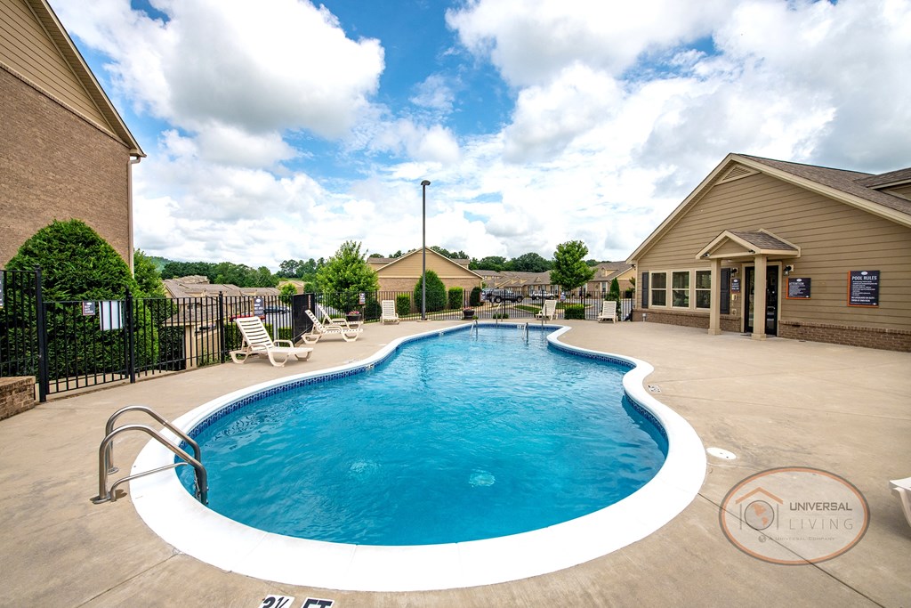a resort style pool with chairs and a building in the background