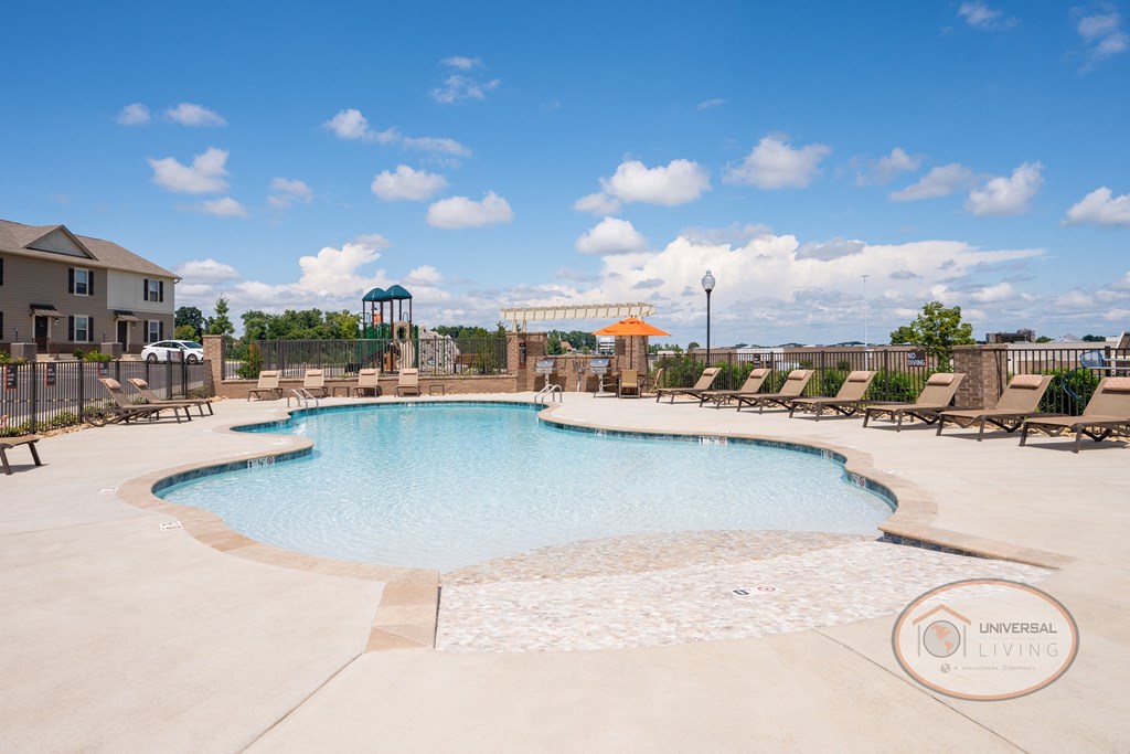 a pool with chairs and umbrellas and a building in the background
