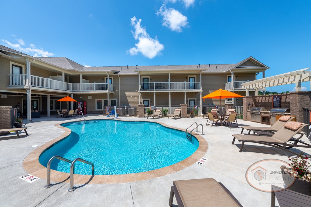 The Villas at Pigeon River, apartment homes in Sevierville, Tennessee. Villas at Pigeon River Swimming pool with lounge chairs surrounded by apartments.