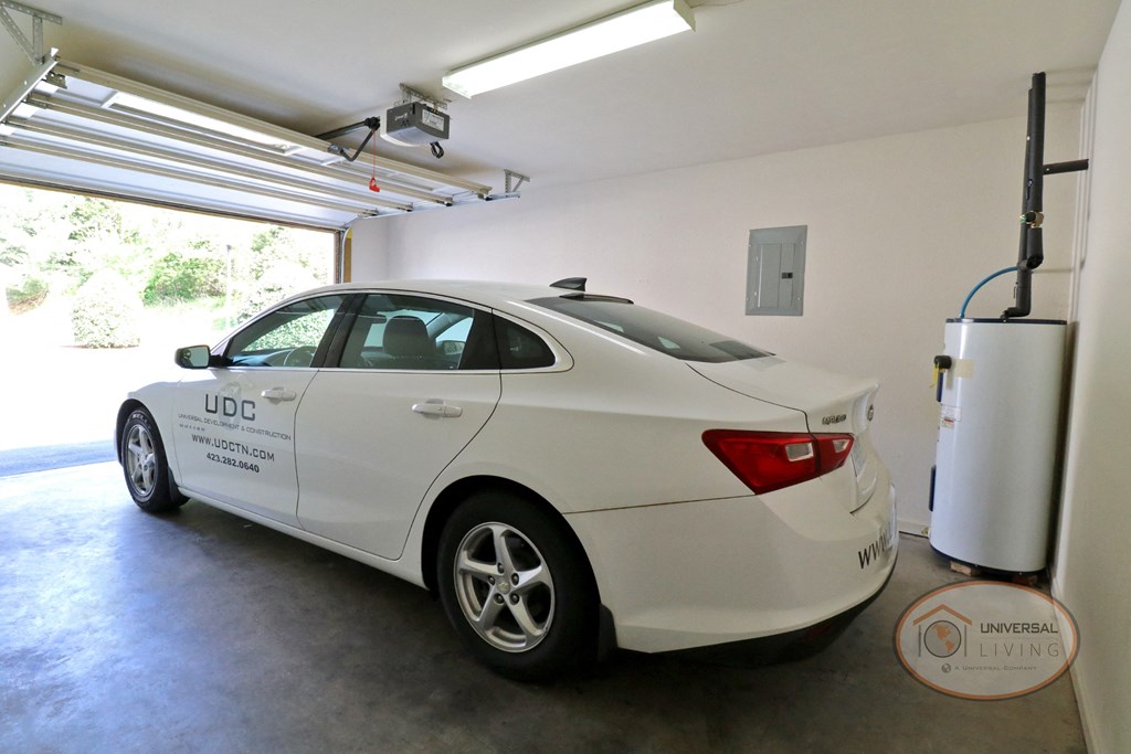 Interior of a garage with a white sedan inside.
