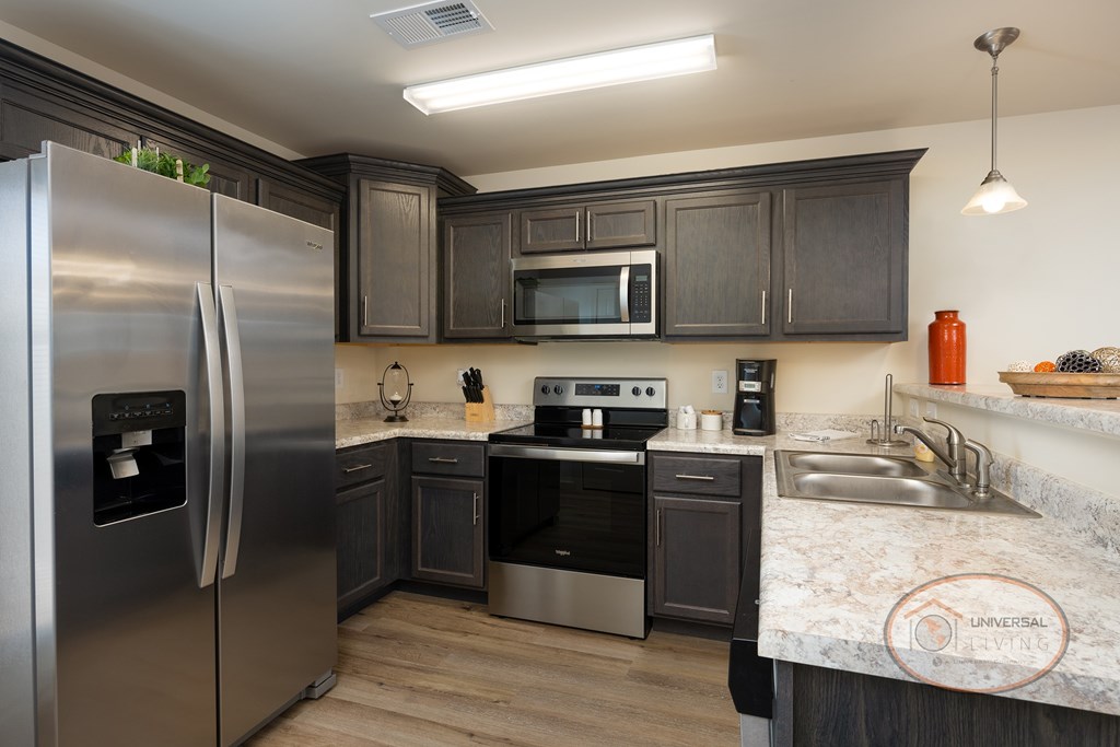 A kitchen with a stainless steel refrigerator and a microwave above the stove.