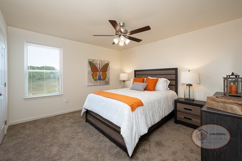 A bedroom with a bed, nightstand, and a ceiling fan.