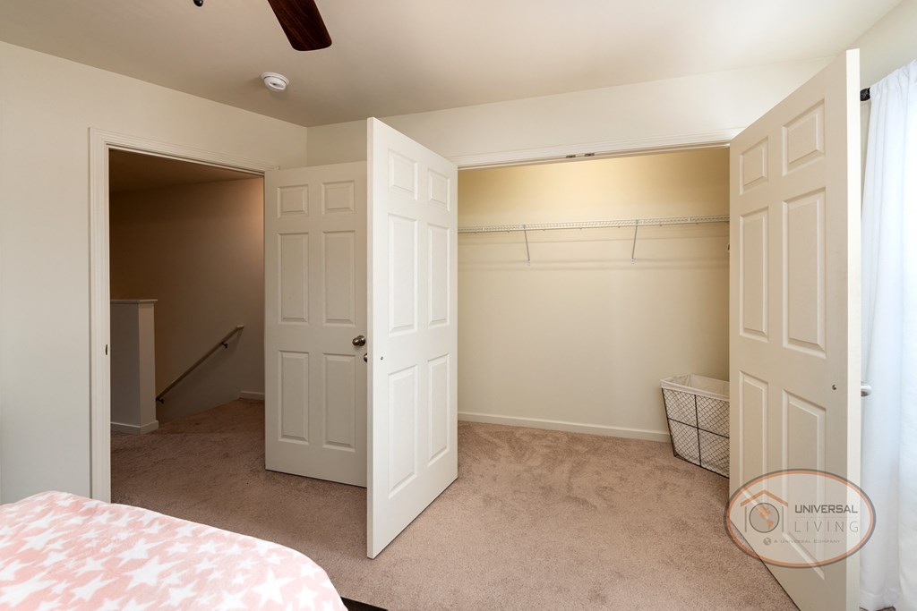 A bedroom with carpet, white walls, and a a large closet.
