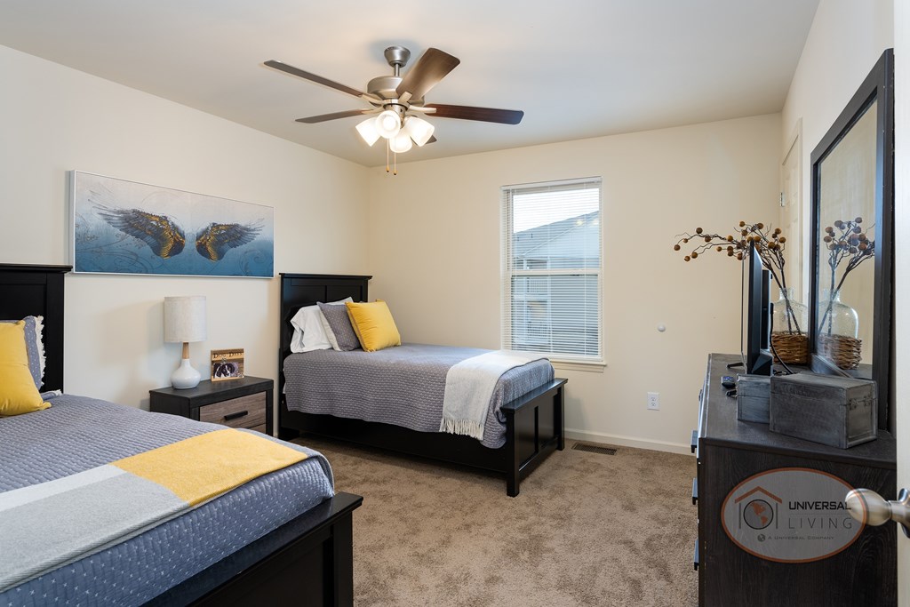 A bedroom with two beds, a ceiling fan, and a painting on the wall.