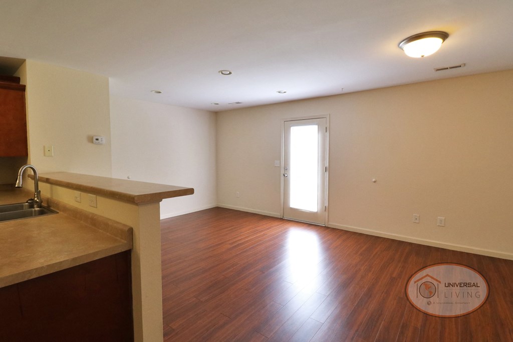 An empty living room with dark wood flooring and a patio door