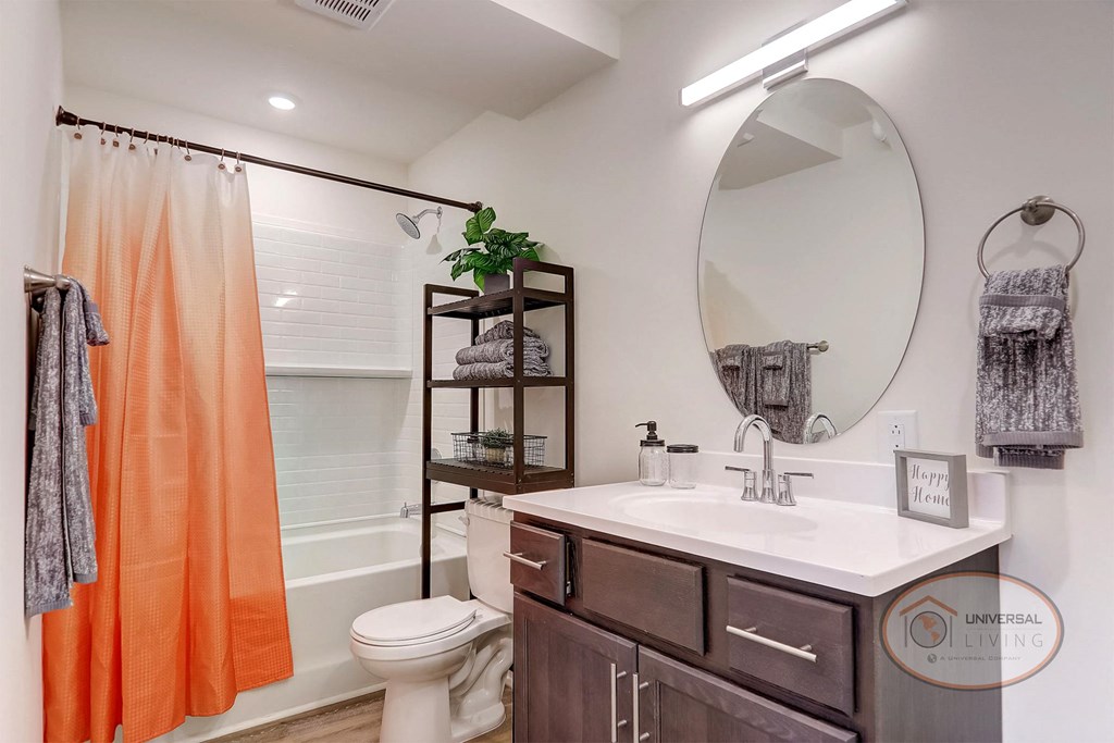 a bathroom with an orange shower curtain and a toilet and a sink