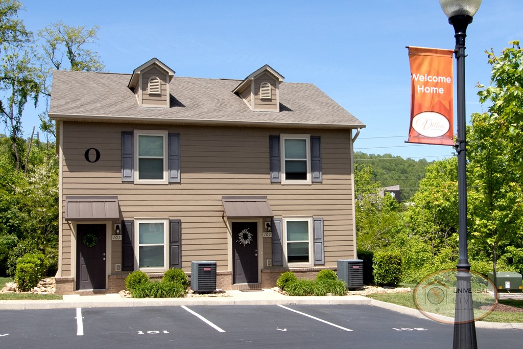 A sign reads "Welcome Home" in front of a townhome.