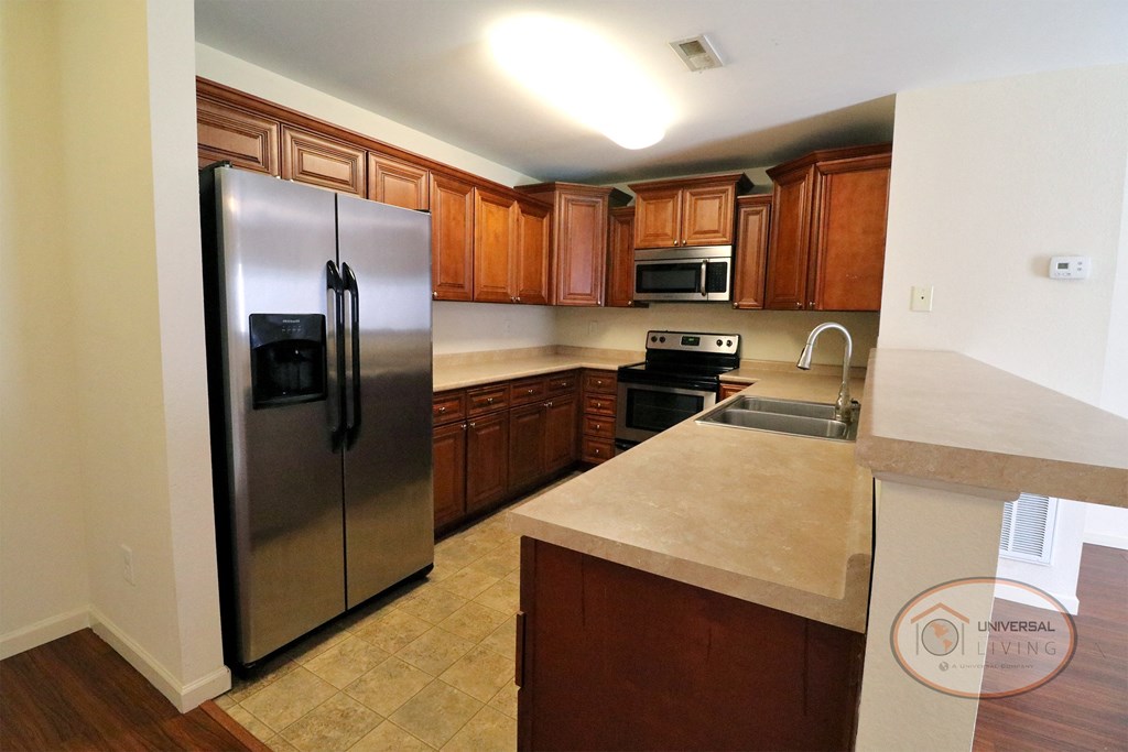 A kitchen with stainless steel appliances and wooden cabinets.