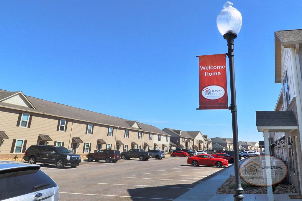 A sign that reads welcome home in front of rows of apartment homes.