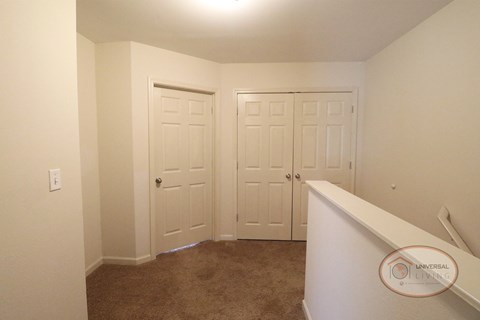 A view of the bedroom and in-unit laundry room from the top of the stairs.