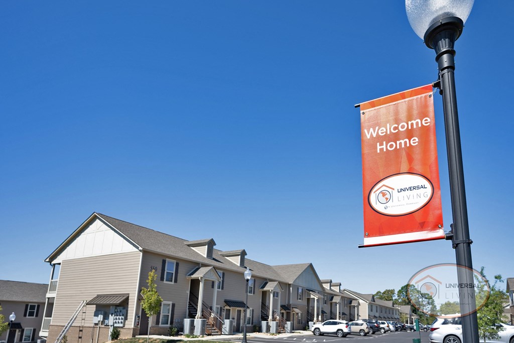 A sign that reads welcome home in front of a row of apartment homes.