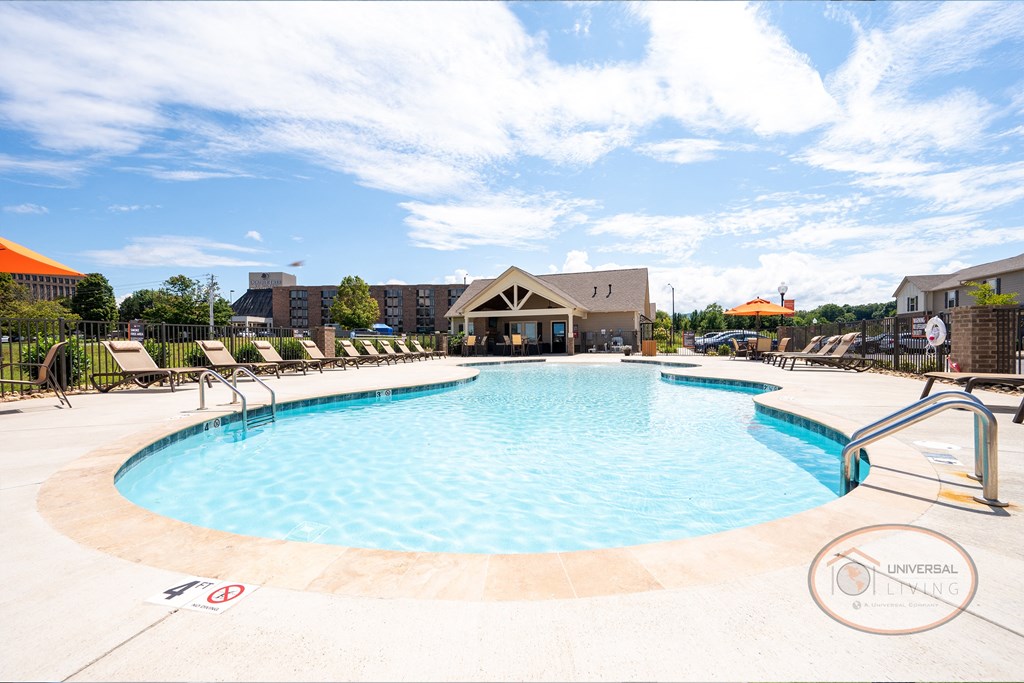 a pool with chairs and a building in the background