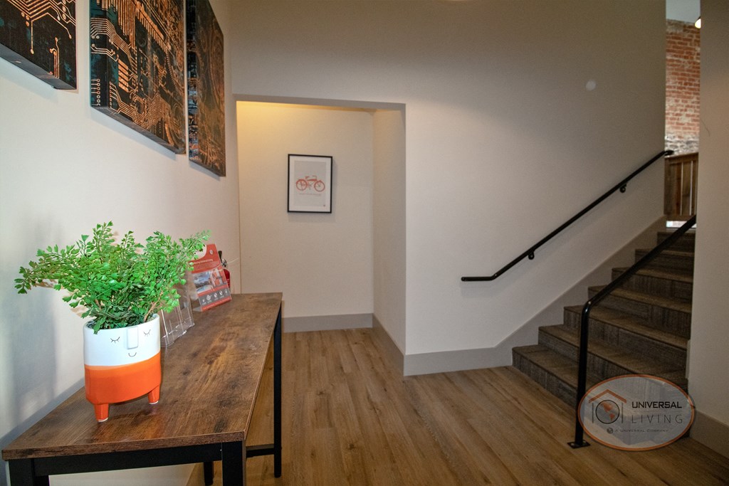 The Henry on main lobby with stairs, a table with a plan in a smiling planter, and a hallway.