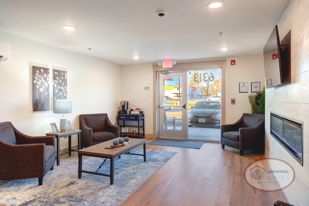 A clubhouse lounge with flat screen TV, fireplace, chairs, tables, and a rug.