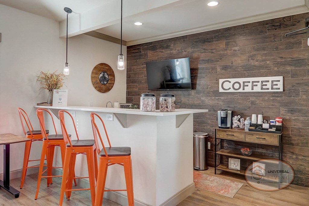 A coffee bar with four orange stools and a flat screen TV.