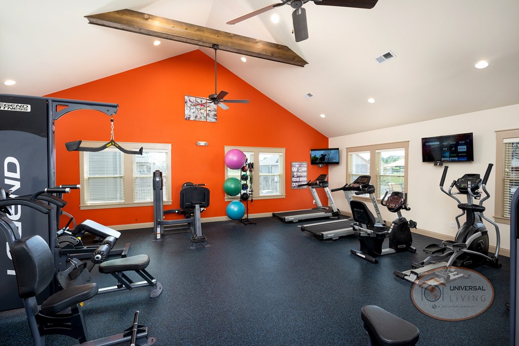 gym with exercise equipment and windows with an orange accent wall