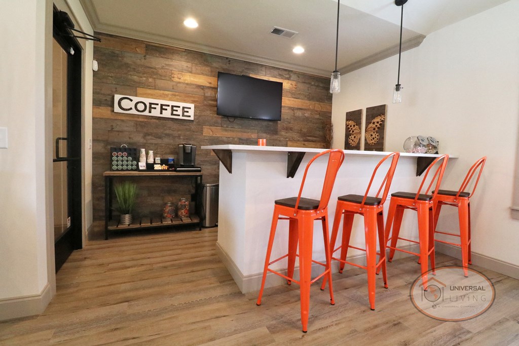a bar with four orange stools in front of a coffee shop with a fireplace