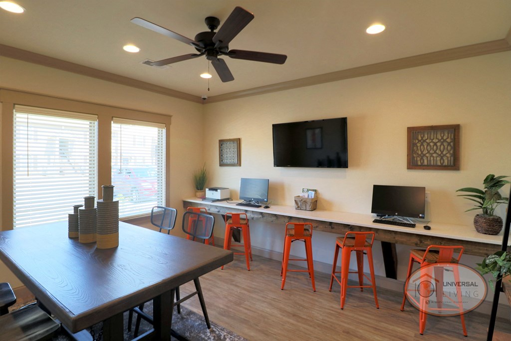 A business center with flat screen TV, computers, a printer, and a desk for working.
