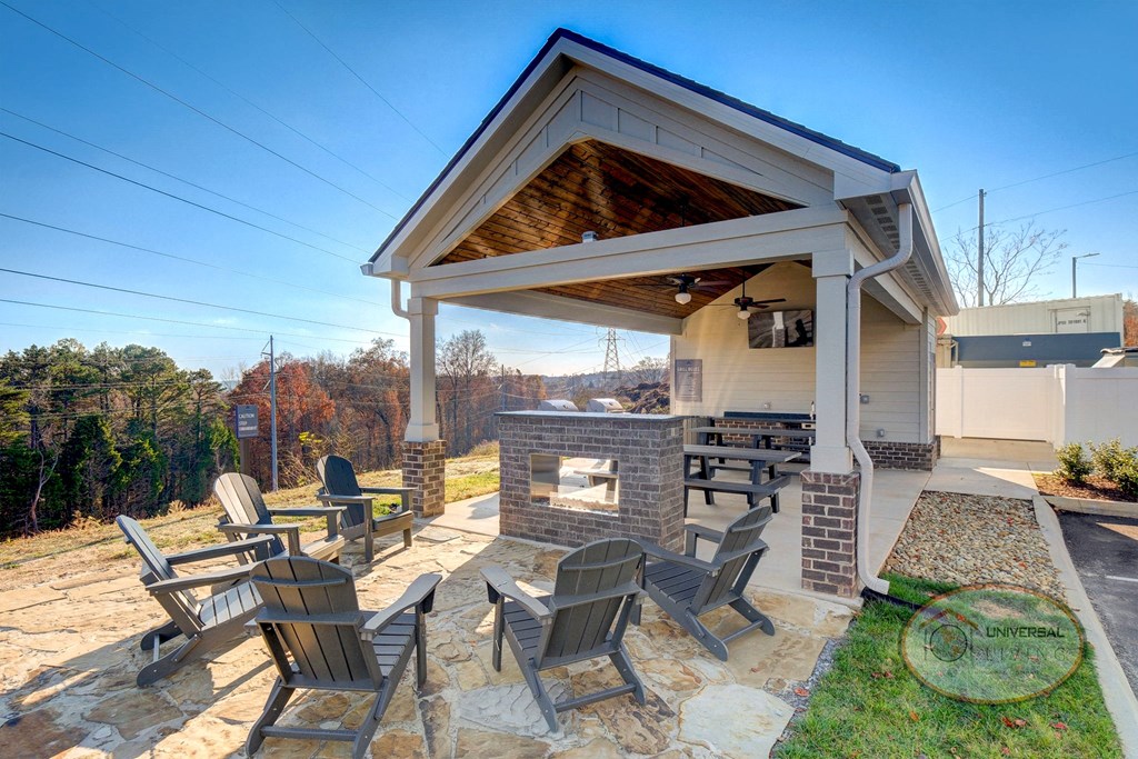 A covered picnic area with a stone fireplace and chairs overlooking the mountains.
