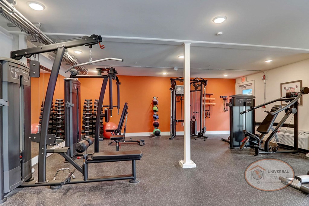 a gym with weights and cardio equipment in a home with orange walls