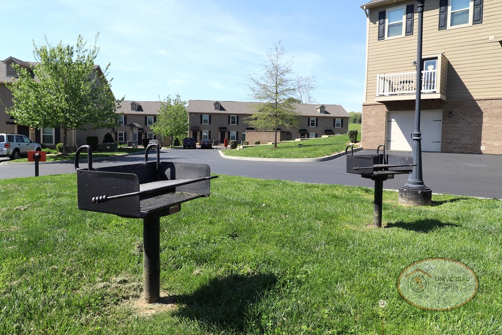 Two personal grills in a grassy area for outdoor gathering.