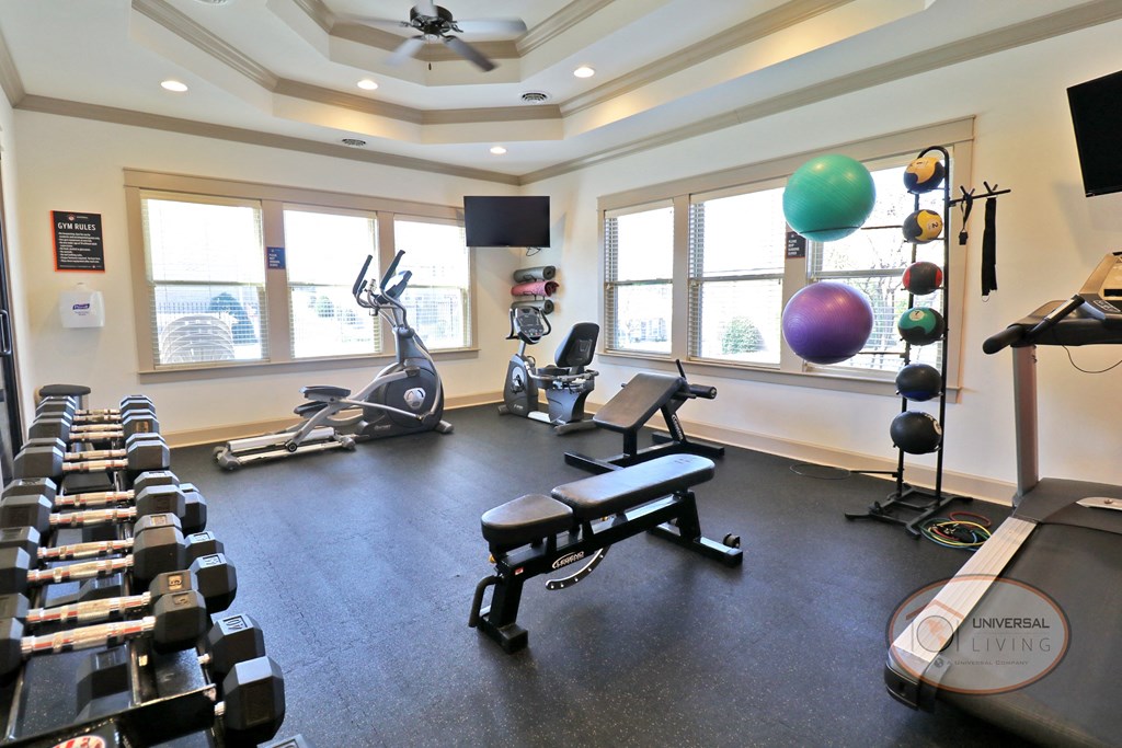 The Villas at Boone Ridge, Apartment Home Community in Johnson City, Tennessee - Fitness Center A fitness center with a wall of mirror and an orange accent wall, featuring weight training equipment and cardio equipment.