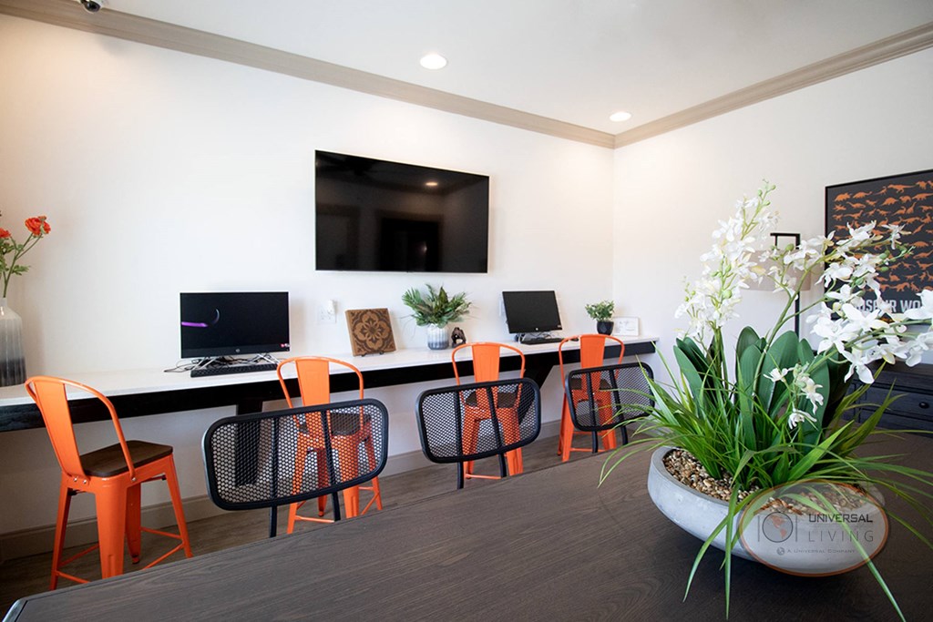A business center with flat screen TV, computers, and a desk for working.