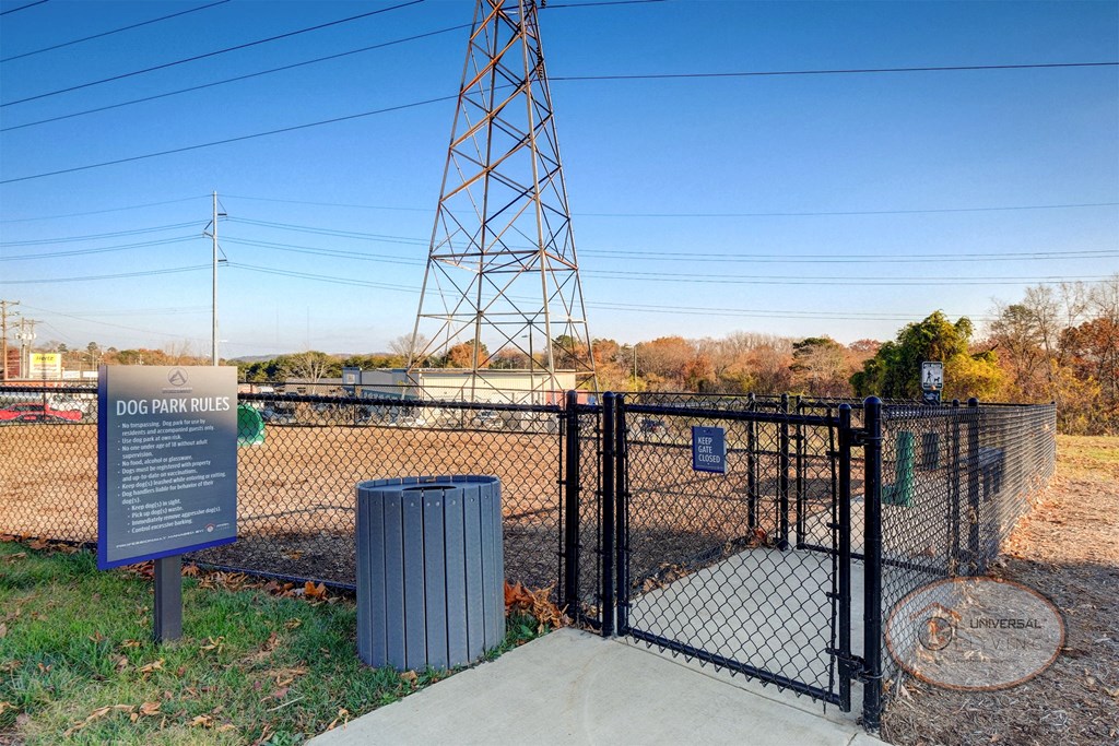 A fenced in dog park with obstacles for pets and a bench.