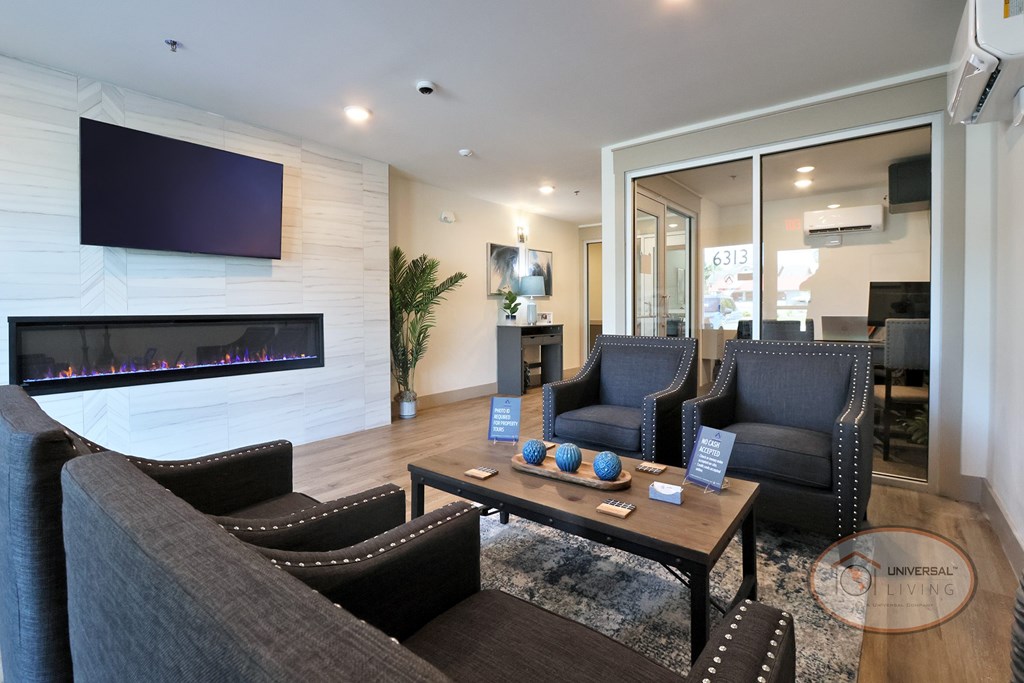 The leasing office with flat screen TV, fireplace, lounge seating, and desk with computer.