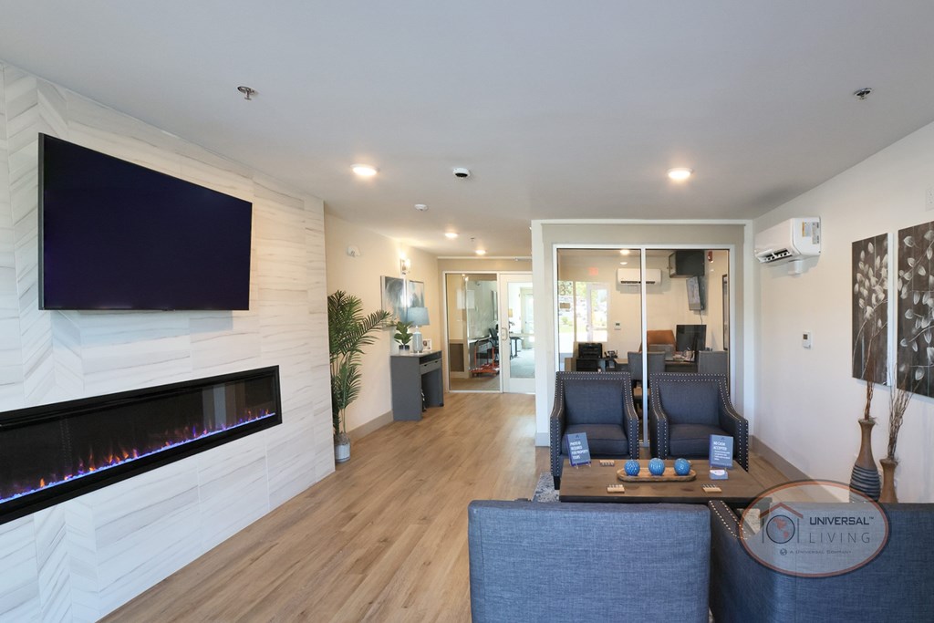 The leasing office with flat screen TV, fireplace, lounge seating, and desk with computer.