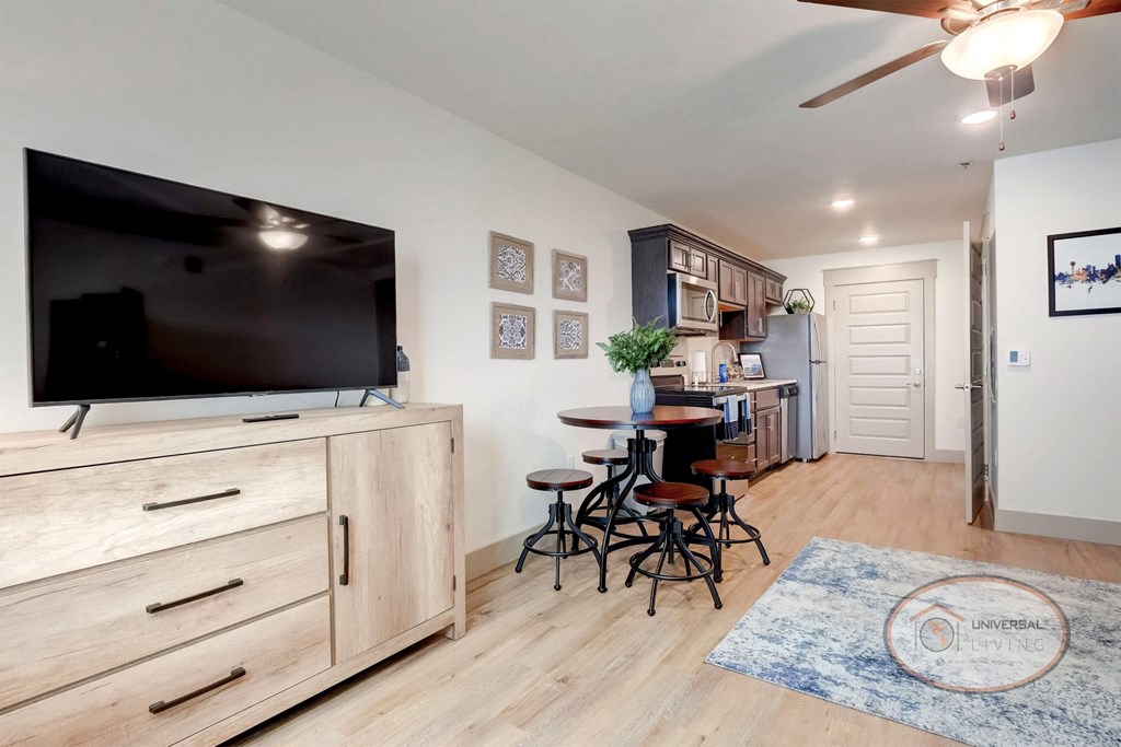 Studio apartment with flat screen TV and kitchen in the background.