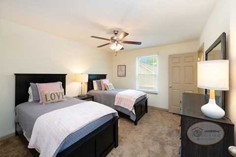 A bedroom with two beds, a ceiling fan, and carpet.