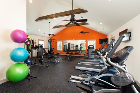 A gym with a variety of equipment including treadmills, exercise balls, and weights.