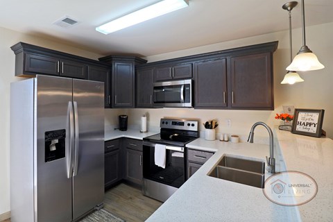 A kitchen with a stainless steel refrigerator and black cabinets.