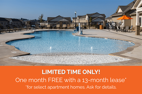 A pool surrounded by apartment buildings with a sign offering a free month with a lease.