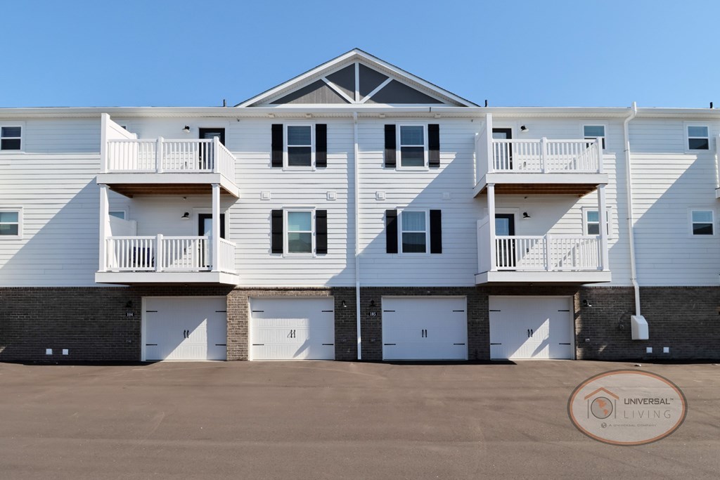 A white and grey apartment building close up photo of the balconies and garage doors.