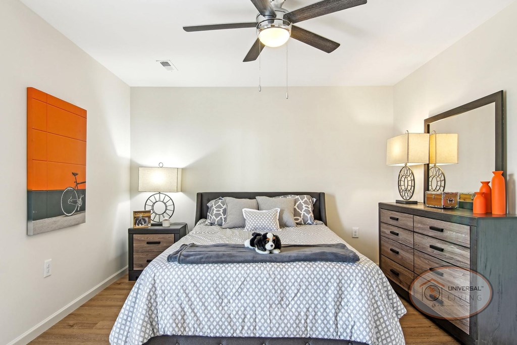 A bedroom with a bed, dresser, and ceiling fan.