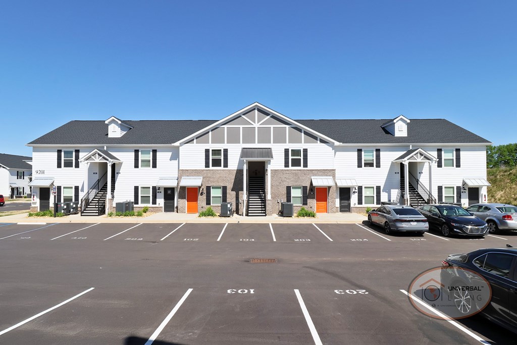 A white and gray apartment building with orange doors and stairs.