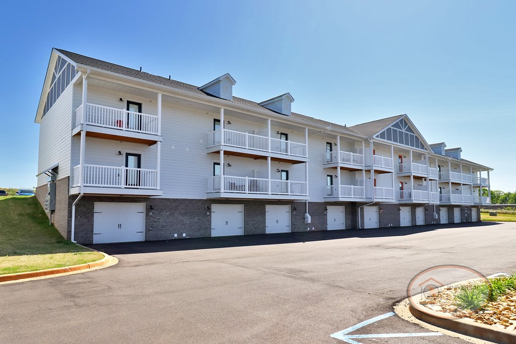 A large white apartment building with multiple balconies and garage doors.