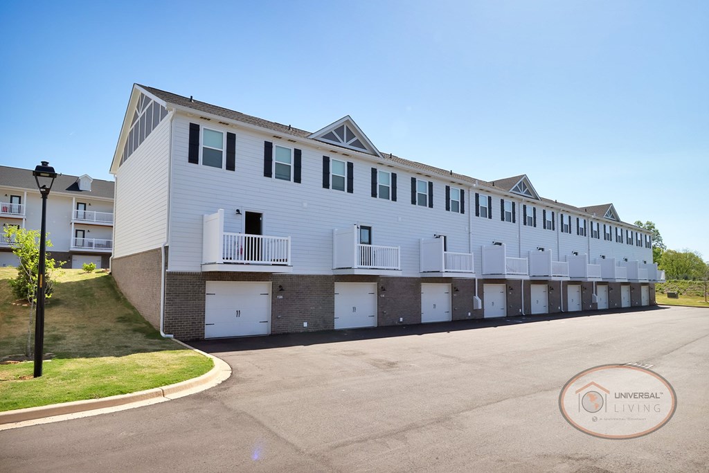 A white and grey apartment building with balconies and garages.