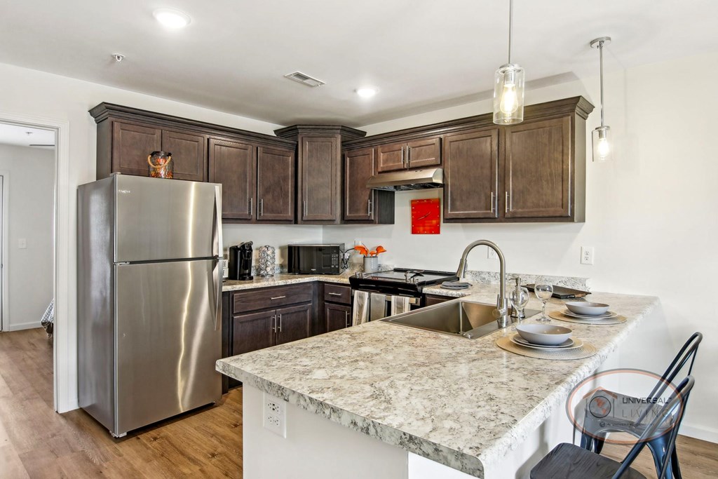 A kitchen with quartz counter tops, dark cabinets, and stainless steel appliances.