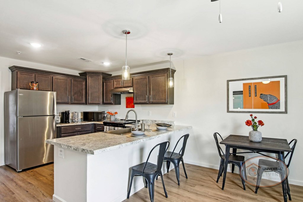 A kitchen with quartz counters, dark cabinets, stainless steel appliances, and a table and chairs.